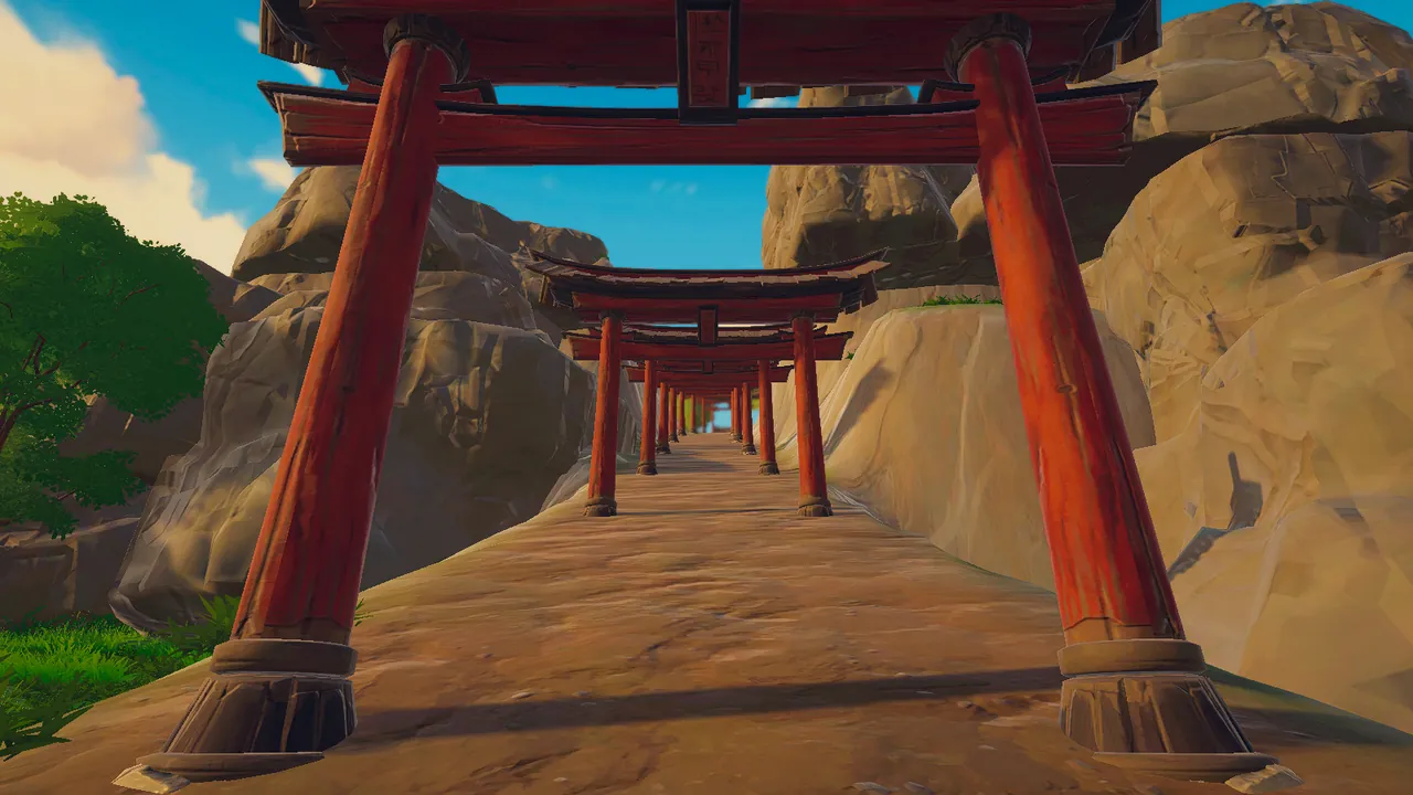Ein Weg führt durch viele rote Torii-Tore zwischen sandfarbenen Felsen